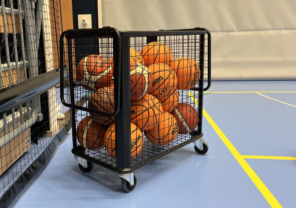 Basketbollar i en korg i en idrottshall.