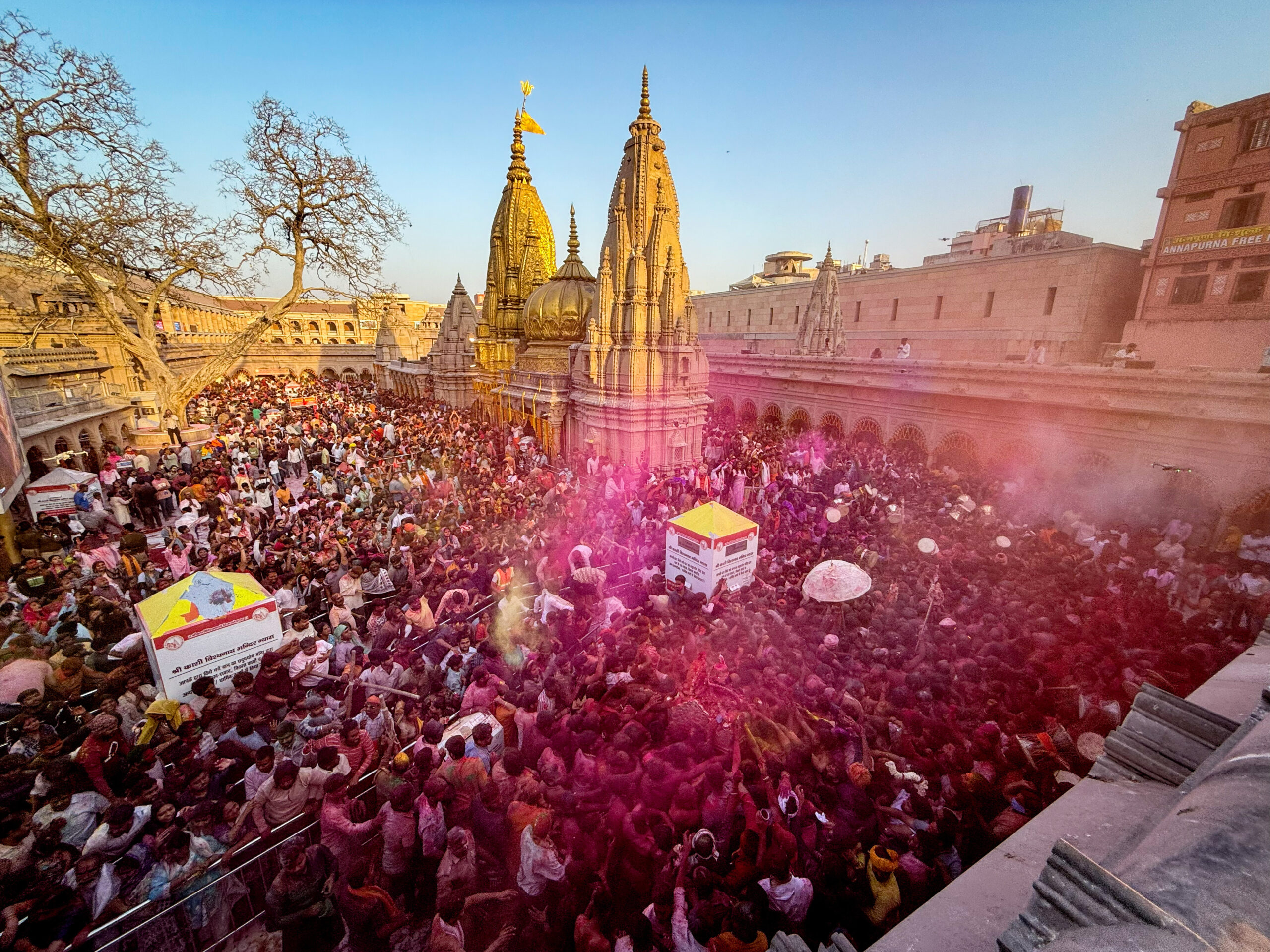 Folkmassa utanför ett hinduiskt tempel, ett lätt moln med rosa färg svävar över folksamlingen.